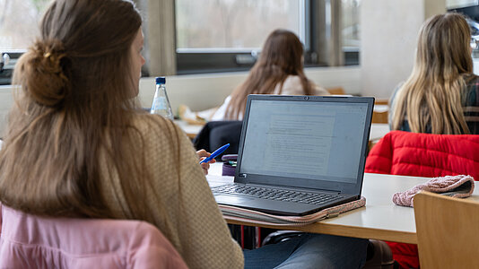 Studentin sitzt in einem Seminar vor dem Rechner und macht sich Notizen