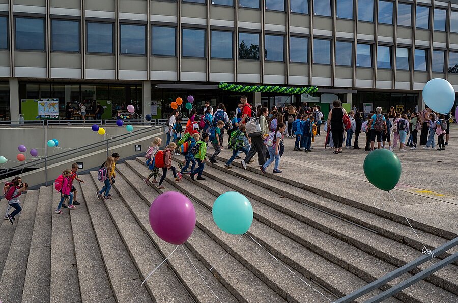 Kinder gehen die Stufen der mit Luftballons geschmückten Außentreppe der PH Ludwigsburg hoch.