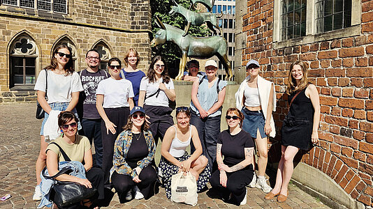 Studierende und Lehrende vor der Skulptur der Bremer Stadtmusikanten